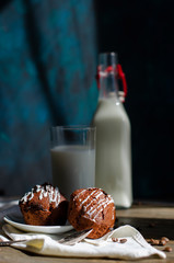 chocolate muffins on a table with a glass of milk and flowers