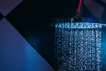 Obraz na płótnie Canvas Drops of water fall from a watering can in the shower in blue light. Water drops close-up. Flow of water. Big round watering can..