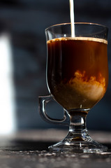 milk is poured into a glass with coffee