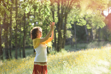 Deep meditation with the hands in mudra of a young woman with sunlight in the field.