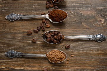 different textures of coffee in spoons on a wooden background, coffee beans, instant coffee, ground coffee
