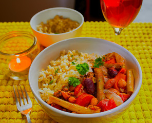 Healthy home made curry and rice in a white dish,there is some wine and a candle in the background.