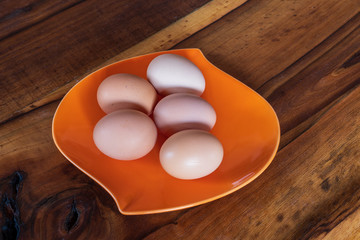 fresh brown and white chicken eggs on a  orange plate on wooden background