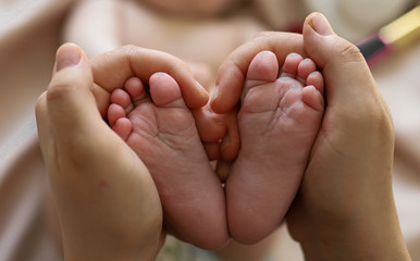 Obraz na płótnie Canvas Bare feet baby in the hands of mom. The heels and toes of the baby