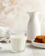 Obraz na płótnie Canvas Glass of milk, jug, cookies. The concept of dairy products, the use of milk, farm products. Copy space. Vertical photo.