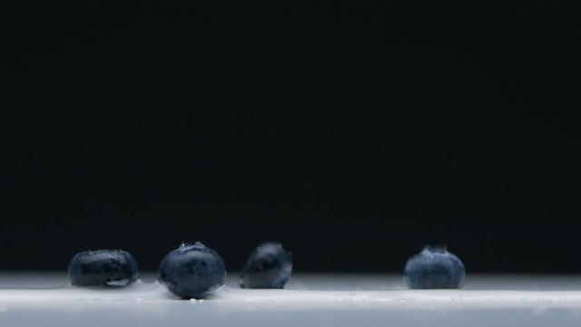 side view of blueberry falling to the empty desk with water splashes Super slow motion from 120 fps