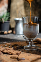 a glass of latte on a table with pieces of dark chocolate and cocoa