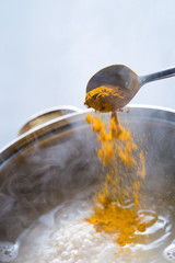 Someone adding the turmeric to the cooked rice