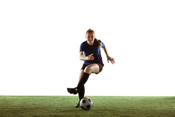 Obraz na płótnie Canvas Young female soccer or football player with long hair in sportwear kicking ball for the goal, training on white studio background. Concept of healthy lifestyle, professional sport, motion, movement.