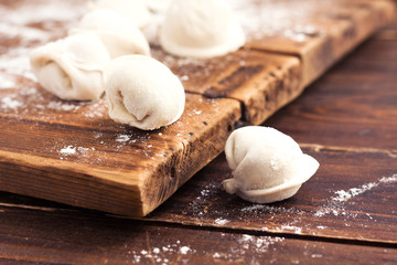 Raw homemade handmade pelmeni (dumplings) with meat on wood