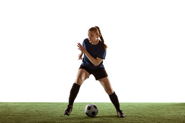 Young female soccer or football player with long hair in sportwear kicking ball for the goal, training on white studio background. Concept of healthy lifestyle, professional sport, motion, movement.