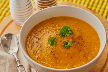 Bowl of pumpkin soup shot from above,there are some condiments in the background.