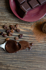 melted chocolate in a spoon on a wooden background with cocoa powder