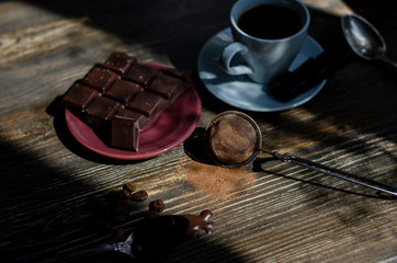 cup of coffee with a piece of chocolate on a wooden background