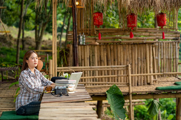  Asian woman woman using laptop checking email news online sitting at park,Communication on distance using internet,Social distancing concept.