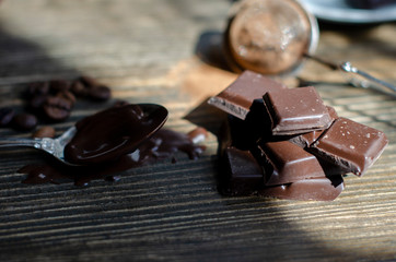 cup of coffee with a piece of chocolate on a wooden background