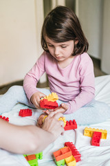 Little girl and mother play Bricks game in bed