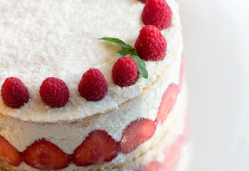 Homemade white cake with raspberries, strawberries and coconut flakes