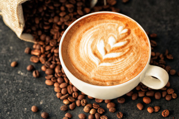 Cup of espresso with coffee beans spilled around it