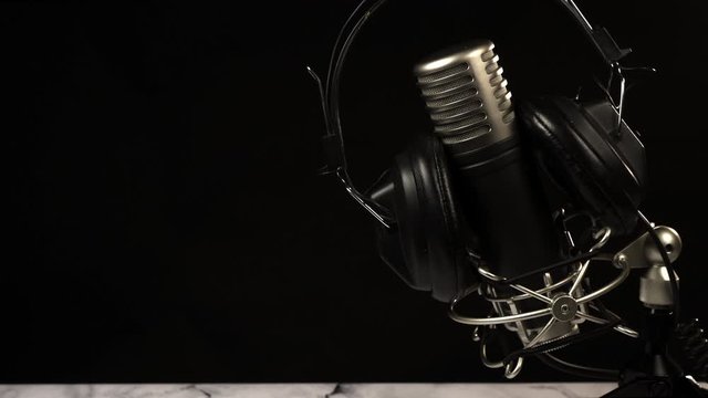 Microphone with headphones on black background. Radio, podcast.