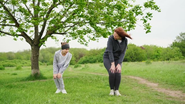 mother and daughter doing spins play sports, do exercises outdoors in the field.
