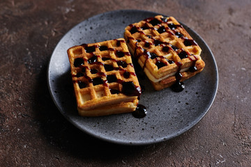 square Viennese waffles with filling on a gray plate and a brown background, sweet waffle breakfast
