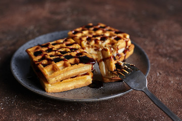 square Viennese waffles with filling on a gray plate and a brown background, sweet waffle breakfast