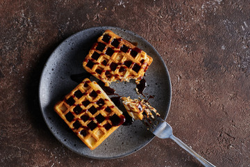 square Viennese waffles with filling on a gray plate and a brown background, sweet waffle breakfast