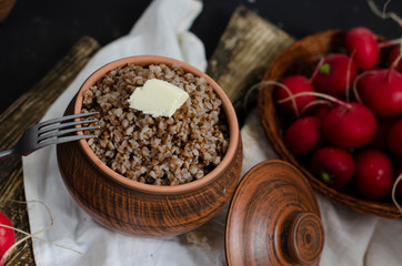 buckwheat porridge in a clay pot with oil and radish
