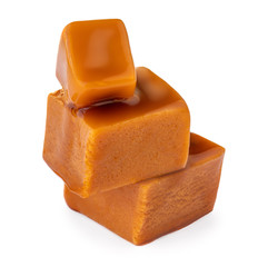Caramel sauce flowing on caramel candies, isolated on white background. Golden Butterscotch toffee candy.