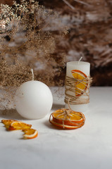 white candles on a table with cotton flowers and dried orange