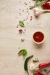 top view of delicious tomato sauce in bowl near herbs and spices on wooden table