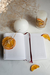 notebook on a table with candles and dried oranges