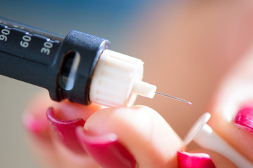 Woman taking blood sample with lancet pen. Diabetes.