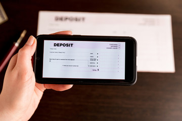 Man Taking Photo Of Cheque To Make Remote Deposit In bank