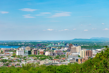 Obraz premium View of Jacques Cartier Bridge from a distance, taken from mount royal over looking Montreal Quebec, nice day with blue sky and clouds