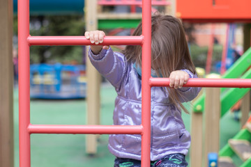 Obraz premium Portrait of a cute blonde little girl wearing a Medical Disposable Face Mask, playing on a playground during quarantine. Stay at home. Isolation. Coronavirus and Air pollution concept.