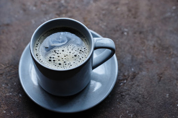 gray cup of coffee on a dish and brown background