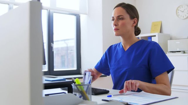 medicine, technology and healthcare concept - female doctor or nurse with computer and medical report working at hospital