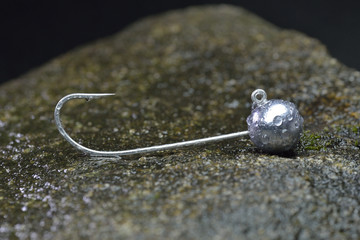 Silver jig head with lead load on wet stone
