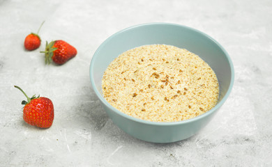 Flax porridge with strawberries in a bowl on a light background and copy space.