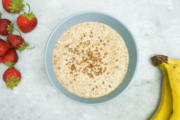 Healthy breakfast. 
Flax porridge with banana and strawberries on a light background.