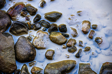 Stones background, water washes stones in a mountain river.