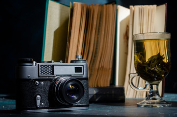 stack of old books on the table with a cup of green tea and a vintage camera