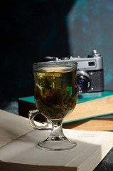 stack of old books on the table with a cup of green tea and a vintage camera