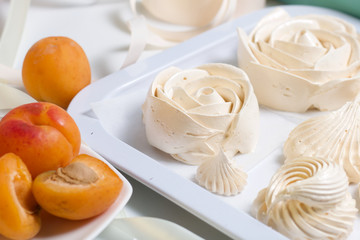 Marshmallows laid out on a tray. Nearby are ripe apricots.