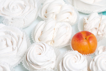 Marshmallows laid out on a tray. Nearby are ripe apricots.