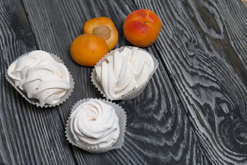Marshmallows laid out on a tray. Nearby are ripe apricots.