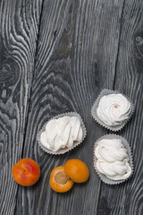 Marshmallows laid out on a tray. Nearby are ripe apricots.