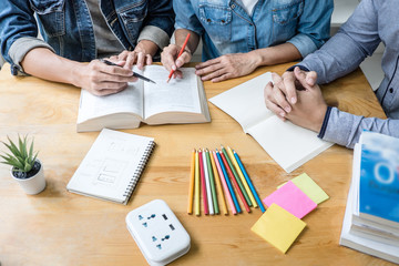 High school tutor or college student group sitting at desk in library studying and reading, doing...